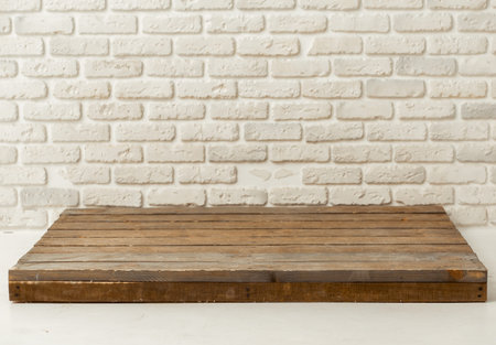 Trendy wooden board lying on white floor against white brick wall. For your merchandising or...