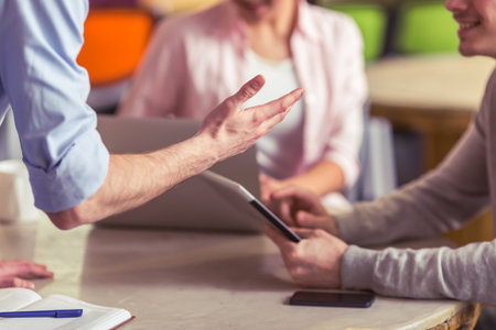 Young freelancers are using gadgets and discussing affairs while working in office, close-up