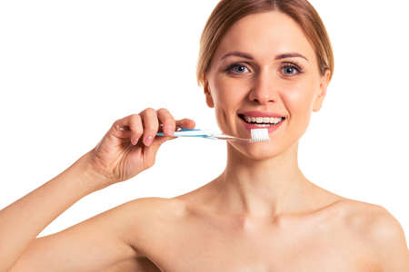 Portrait of naked beautiful young woman holding a toothbrush and smiling, isolated on a white backgroundの写真素材