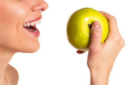 Portrait of beautiful young woman smiling and holding an apple, isolated on a white background, croppedの写真素材