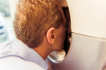 Handsome middle aged patient is examining his face with a modern medical equipment, close up