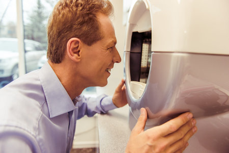 Handsome middle aged patient is examining his face with a modern medical equipment, close up