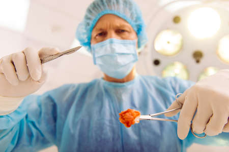 A surgeon is holding medical instruments while doing surgery in a modern operating room, bottom view, close upの写真素材