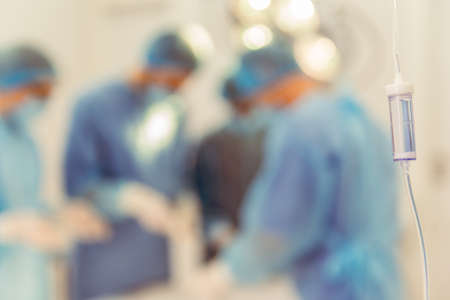 Team surgeons are performing an operation in a modern operating room, a drip in the foregroundの写真素材