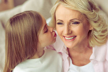 Portrait of beautiful granny smiling while her granddaughter kissing herの写真素材