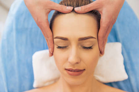 Top view of beautiful young woman getting a face massage, lying with closed eyesの写真素材