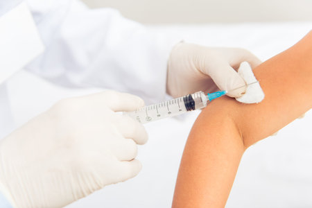 Handsome middle aged pediatrician is making an injection to a little girl, close-up