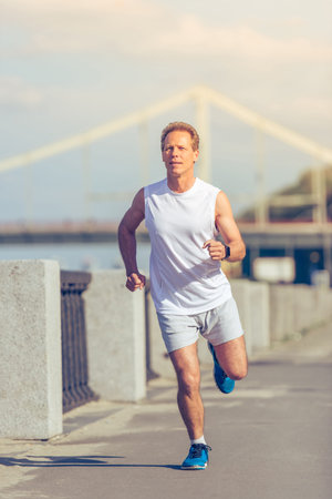 Handsome middle aged man in sports uniform is running in the morningの写真素材