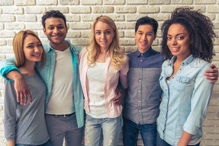 Beautiful young people of different nationalities are looking at camera and smiling, standing...
