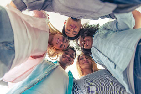 Bottom view of young people of different nationalities standing in circle, looking at camera and smilingの写真素材