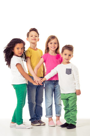 Full length portrait of cute little kids in casual clothes holding hands together, looking at camera...