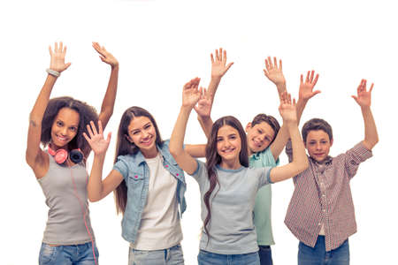 Group of teenage boys and girls is keeping hands up, looking at camera and smiling, isolated on whiteの写真素材