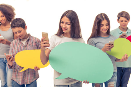 Group of teenage boys and girls is holding speech bubbles, using smartphones and smiling, isolated...