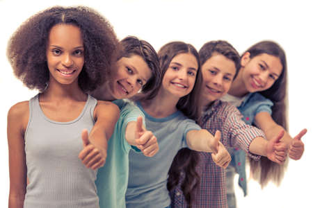Group of teenage boys and girls is showing Ok sign, looking at camera and smiling, standing in row one by one, Afro American girl in the foregroundの写真素材