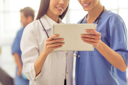 Cropped image of two beautiful female doctors using a tablet and smilingの写真素材