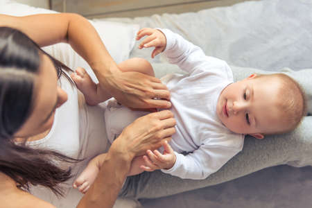 Top view of beautiful young mom and her sweet little baby looking at each other and smiling, spending time together at homeの写真素材
