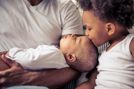 Beautiful young Afro American family spending time together. Little baby is sleeping in dad's arms...