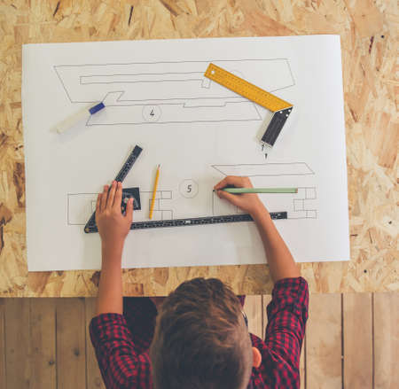 Top view of handsome teenage carpenter drawing his new project in the workshopの写真素材