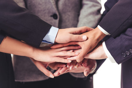 Cropped image of beautiful business people in suits holding hands together