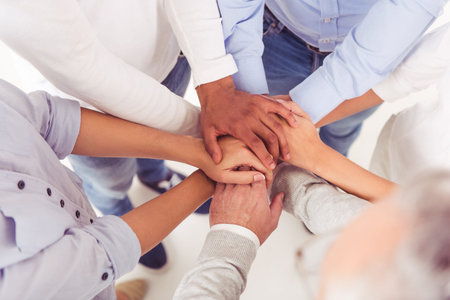 Cropped image of beautiful business people in smart casual wear holding hands togetherの写真素材