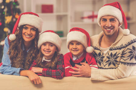 Happy young family looking at camera and smiling while celebrating Christmas at homeの写真素材