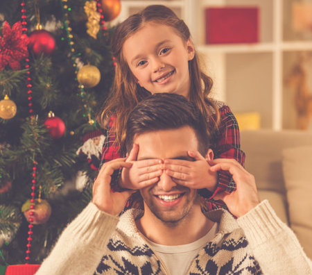 Handsome young father and his charming little daughter celebrating Christmas at homeの写真素材