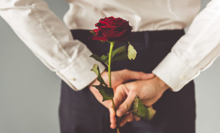 Cropped image of romantic guy holding a red rose behind his backの写真素材