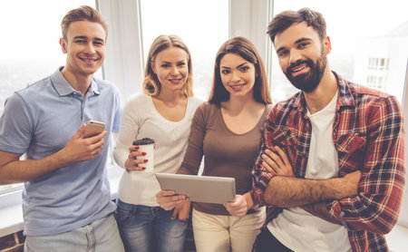 Beautiful young business people are using a digital tablet, talking and smiling during coffee breakの写真素材