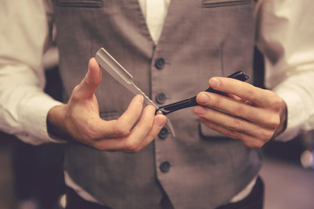 Cropped image of barber in stylish classic wear holding a straight razorの写真素材