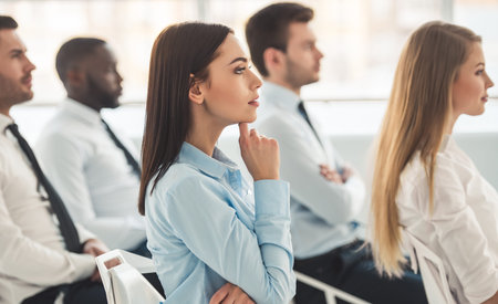 Successful business people are listening to the speech and smiling while sitting at the conference
