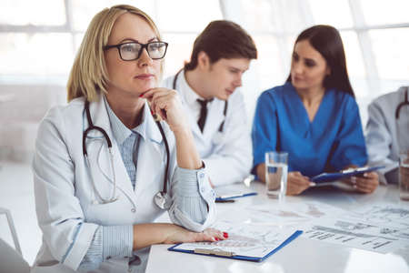 Successful medical doctors are sitting at the conference. Beautiful mature female doctor in the foregroundの写真素材