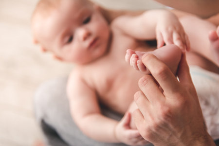 Young dad is stroking his baby's tender foot, close-upの写真素材