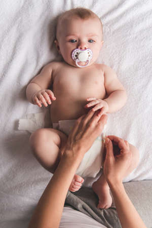 Young mom is changing her cute baby diaperの写真素材