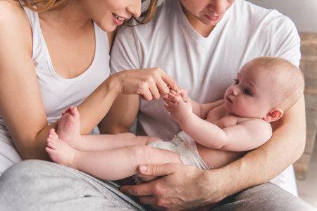 Beautiful young parents are playing with their cute baby and smiling