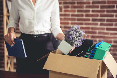Getting fired. Cropped image of beautiful young business woman in formal wear packing her stuff into the boxの写真素材