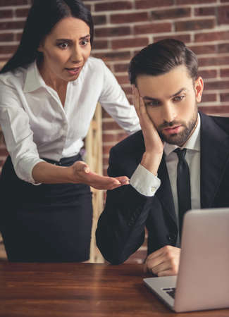 A little problem. Beautiful business couple are looking at laptop shockedの写真素材