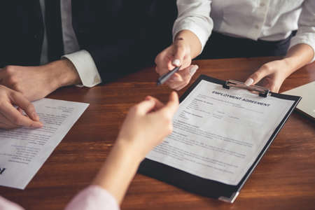 Cropped image of beautiful couple of employers in suits conducting a job interview while sitting in officeの写真素材