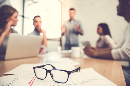 Beautiful business people are using gadgets, listening to their colleague and smiling during the conference in officeの写真素材