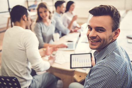 Beautiful business people are using gadgets, talking and smiling during the conference in office