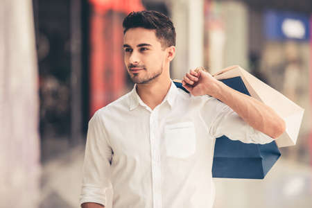 Handsome guy with shopping bags is smiling while doing shopping in the mallの写真素材
