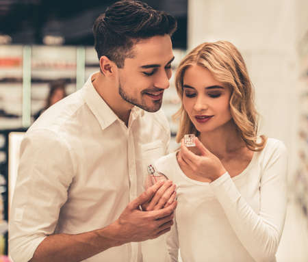 Beautiful couple is choosing perfumes and smiling while doing shopping in the mallの写真素材