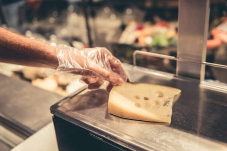 At the supermarket. Cropped image of worker weighing cheeseの写真素材