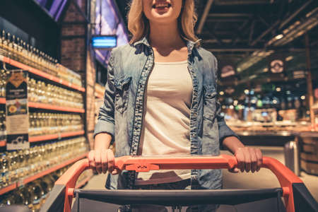 Cropped image of beautiful woman with a shopping cart smiling while doing shopping at the supermarketの写真素材