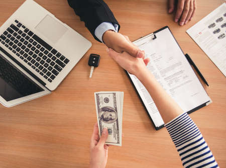 Visiting car dealership. Top view of sales manager shaking hand with a clientの写真素材