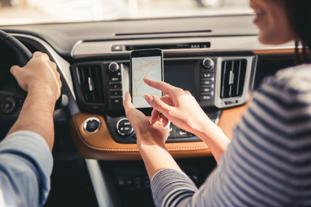 Beautiful couple is driving a car and using digital map on the smart phoneの写真素材
