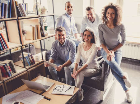 Successful young business people are looking at camera and smiling while working in officeの写真素材
