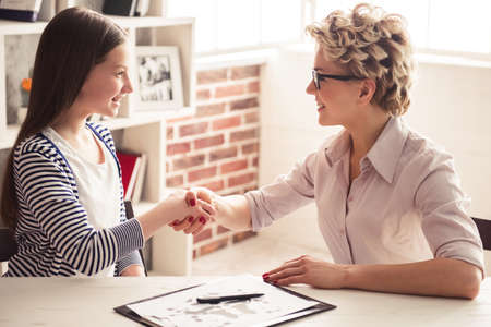 Teenage girl is visiting psychotherapist, they are shaking hands during the session in office