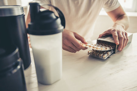 Cropped image of handsome young sportsman preparing sport nutrition in kitchen at homeの写真素材