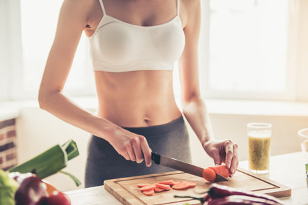 Cropped image of beautiful young sportswoman cooking healthy food in kitchen at homeの写真素材