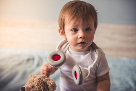 Cute baby boy with headphones is looking away and smiling